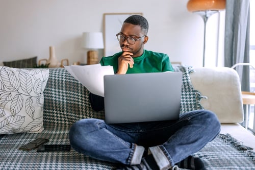 man sitting on floor with laptop doing taxes