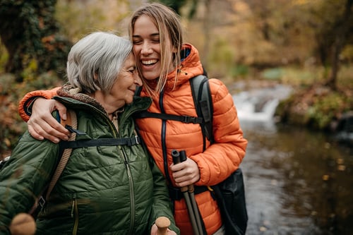 active mother and daughter hiking and laughing multi generation