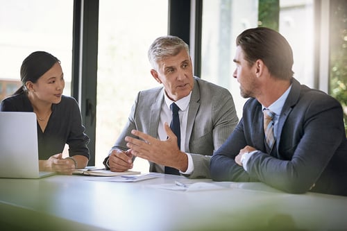 close up of three coworkers discussing something in a modern office setting
