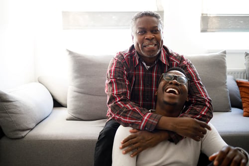 father and son laughing on couch multi generation