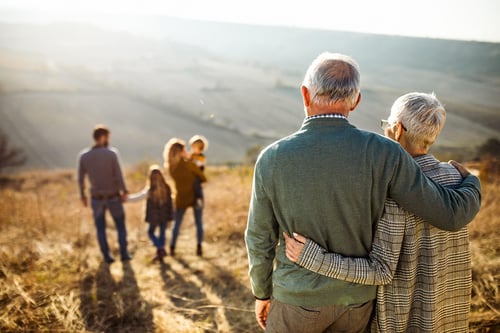 mature couple looking at family outdoors multi generation