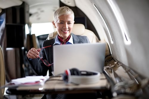 mature professional woman on a laptop while traveling in a private plane