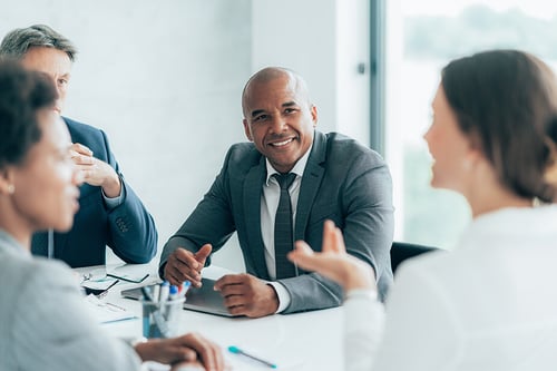smiling businessman seated in a conference room with coworkers