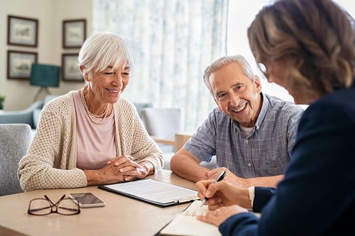 smiling mature couple meeting with a female advisor at home
