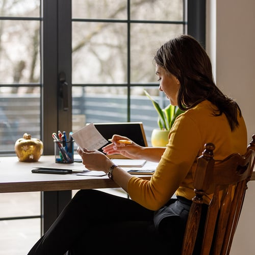 young woman alone at desk in front of window