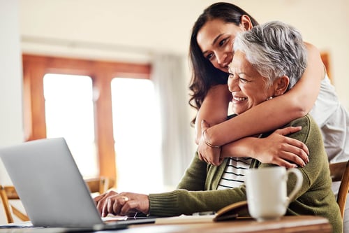 young woman hugging her grandmother on laptop multi generation